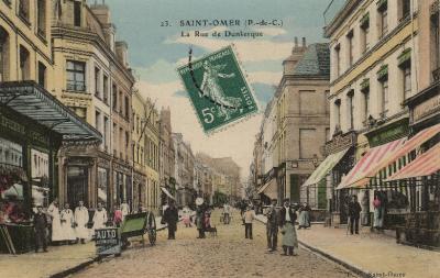 On se trouve ici au carrefour avec les rues de Valbelle et rue St Sépulcre,c'est un endroit très animé ou l'on voit les commerçants sortir devant leur étal. Sur la gauche une charrette à bras qui servait au transport des marchandises.